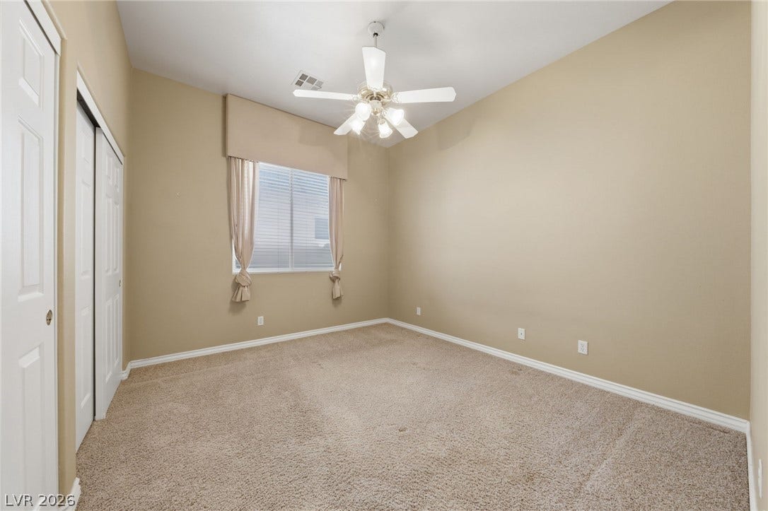 High ceilings and neutral carpeting define this versatile secondary bedroom space.