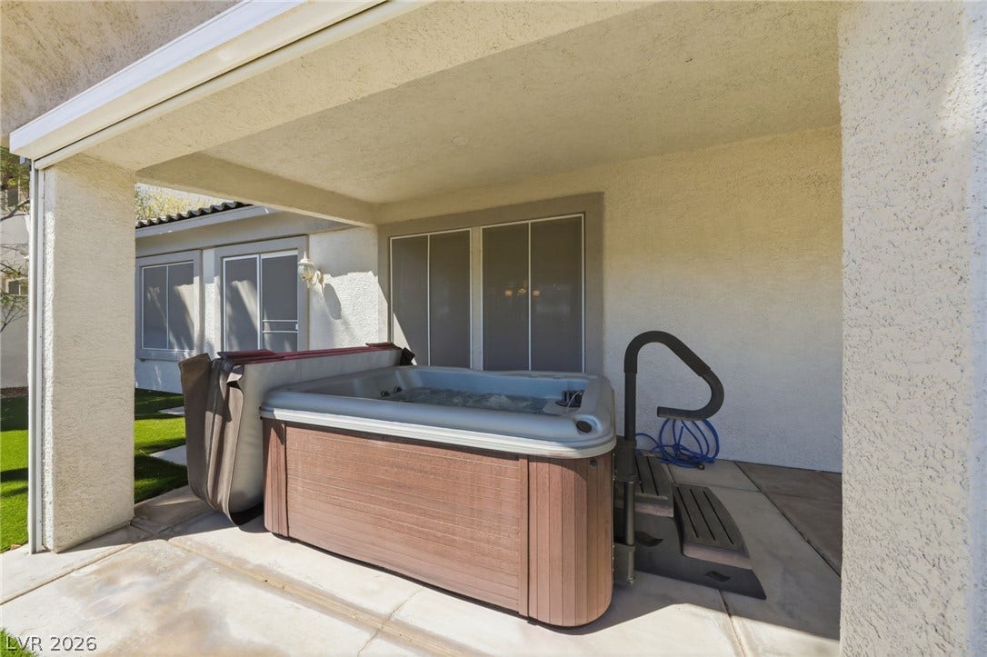 Sheltered by a covered patio, a private hot tub anchors this concrete outdoor space.