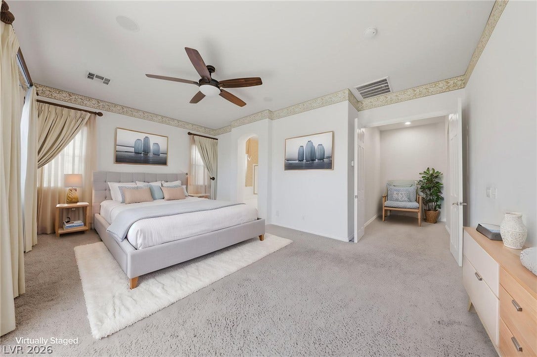 Soft carpeting pairs with neutral walls and delicate wallpaper borders in this peaceful bedroom.