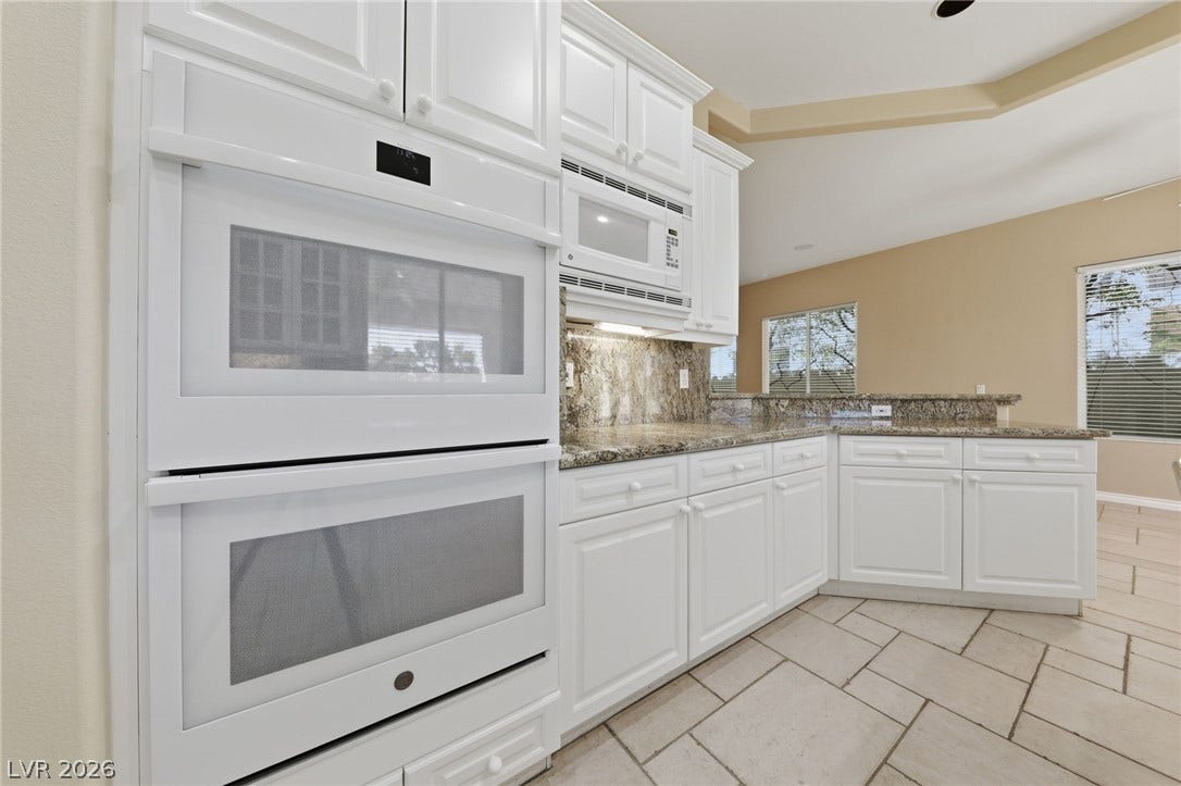Gleaming stone countertops and integrated appliances define this spacious culinary space with vaulted lines.