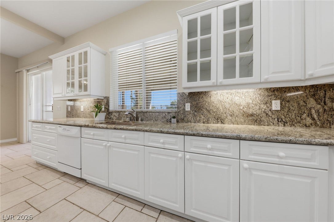 Rich granite countertops pair elegantly with classic white cabinetry and tile flooring.