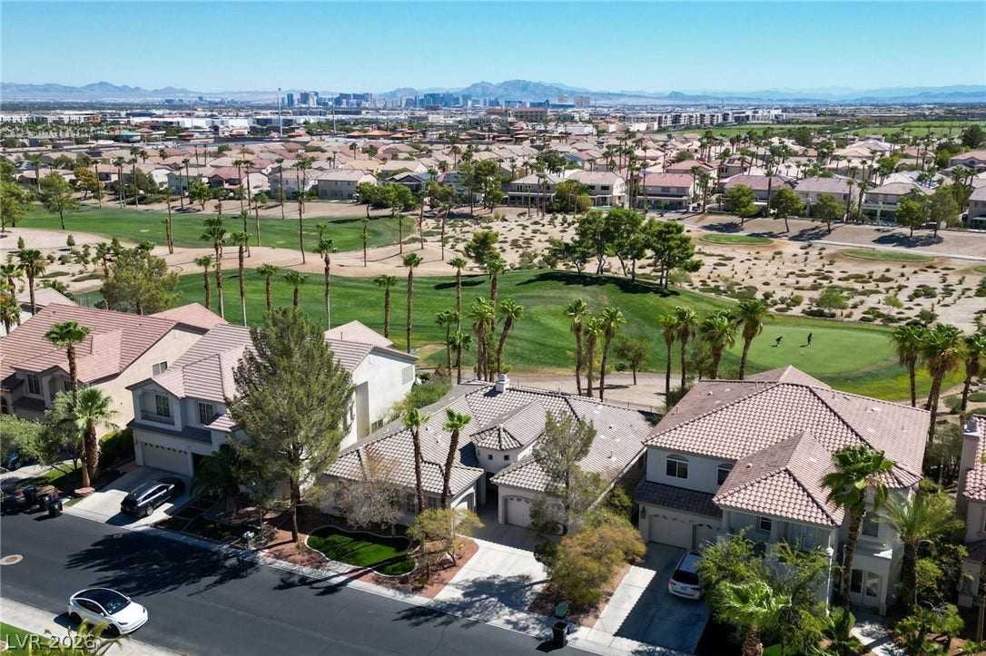 A sweeping aerial view showcases the surrounding neighborhood, golf course, and distant mountain skyline.