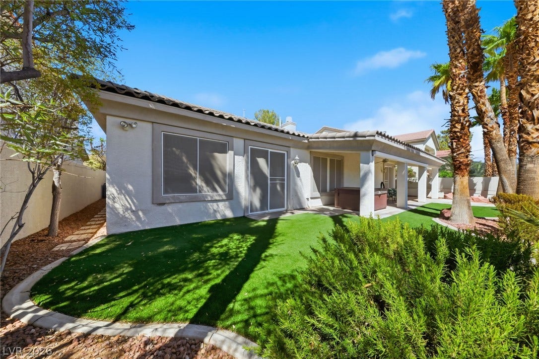 A neatly manicured lawn borders the covered patio of this single-story home.