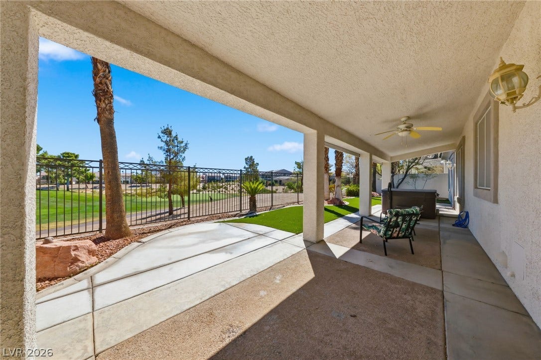 An inviting covered patio offers a cool concrete surface overlooking the manicured fairway views.