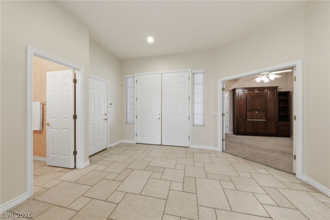 An inviting entrance foyer features neutral tile floors, high ceilings, and wide doorways.