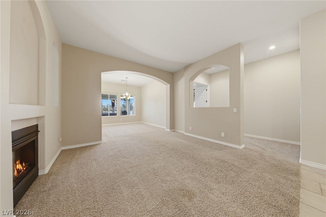 Arched doorways and a cozy fireplace define this open, carpeted living area.