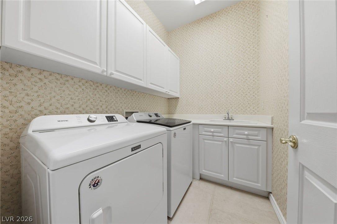 Ample built-in cabinetry and a dedicated utility sink maximize functionality in this laundry space.