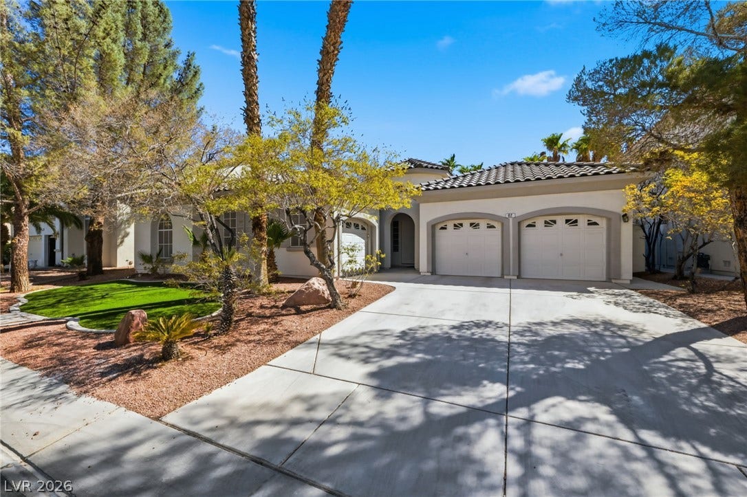 A spacious concrete driveway leads past desert landscaping to a classic Spanish tile roof.