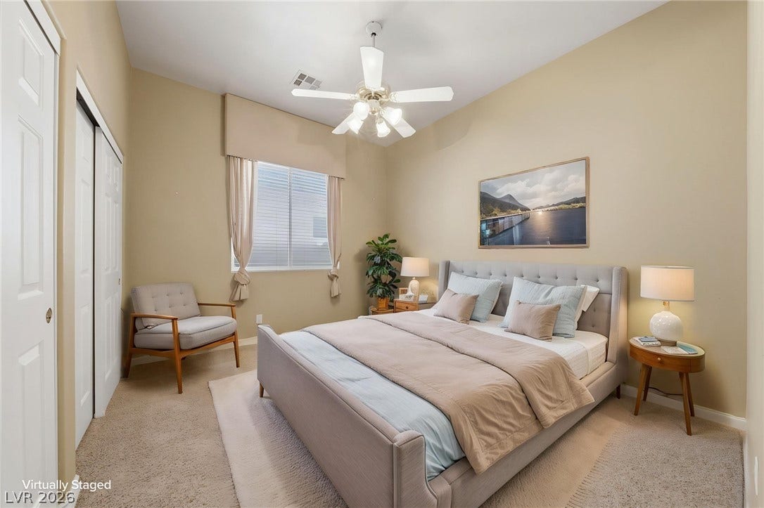 A spacious bedroom features comfortable carpeted flooring and high ceilings.
