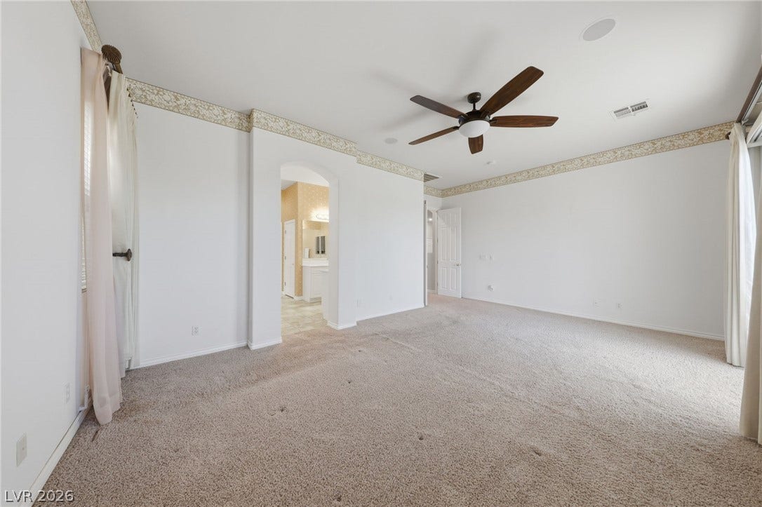 A spacious layout and neutral carpeting define this airy bedroom suite.