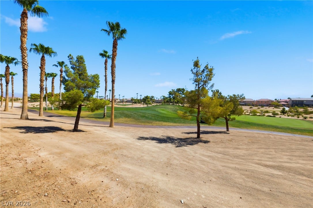 Lush fairways and mature palm trees define this expansive golf course setting under blue skies.