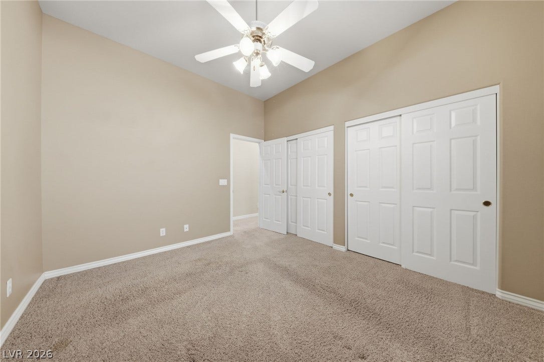 High ceilings and neutral carpet define this comfortable secondary bedroom.