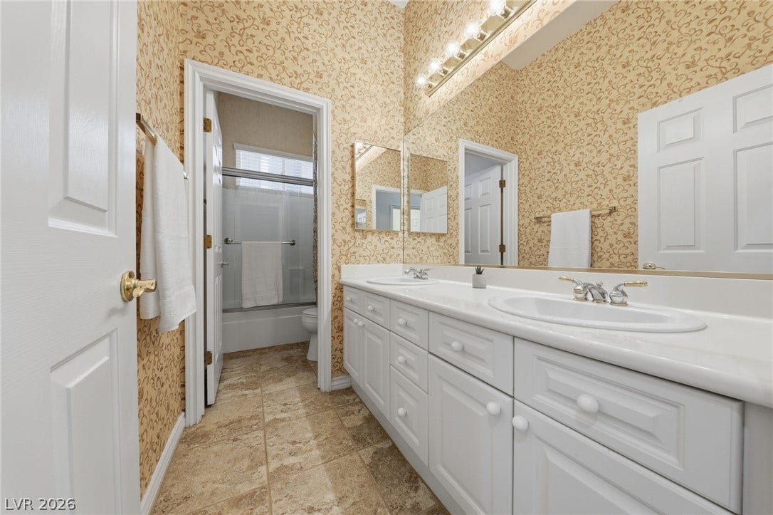 An expansive vanity counter and classic tile flooring define this functional double-sink bathroom.