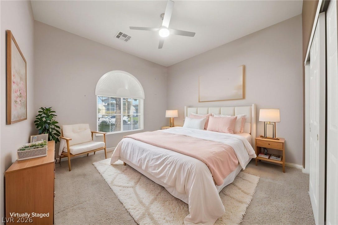 High ceilings and arched window details enhance this light-filled bedroom with classic carpet flooring.