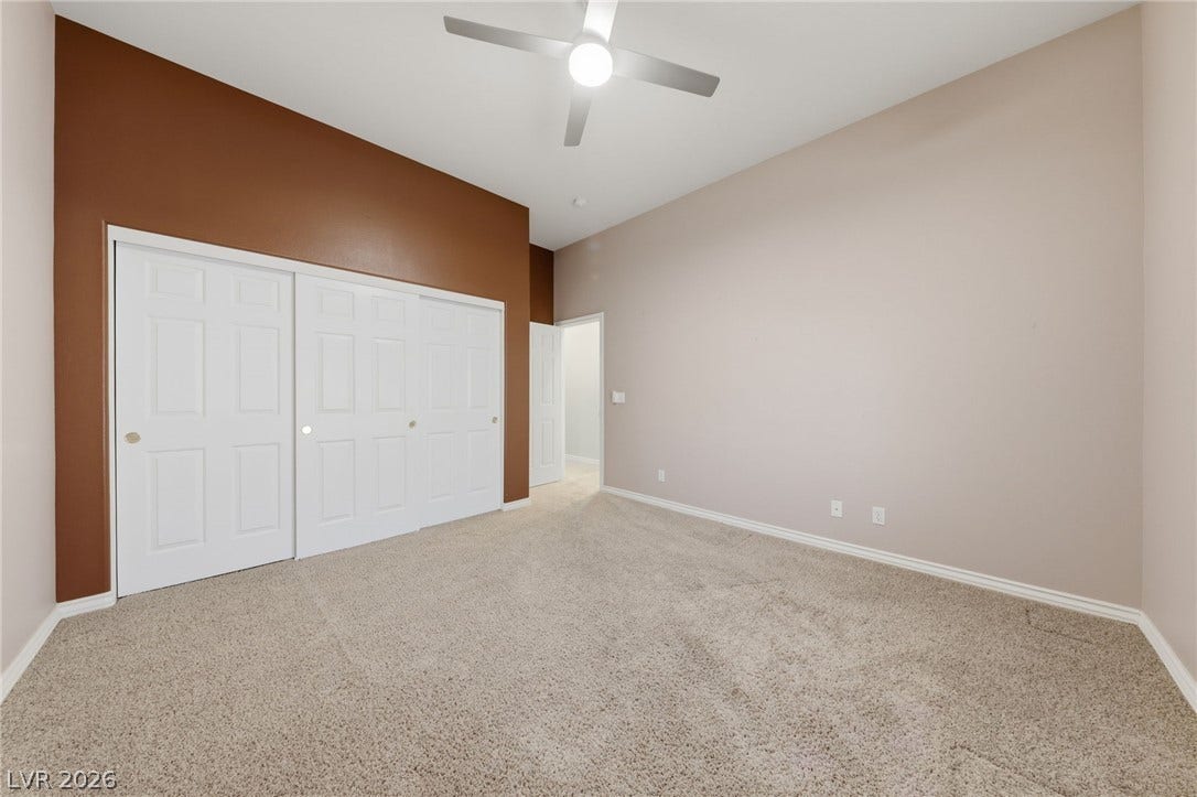 A spacious bedroom features neutral-toned walls, soft carpeting, and generous closet space.
