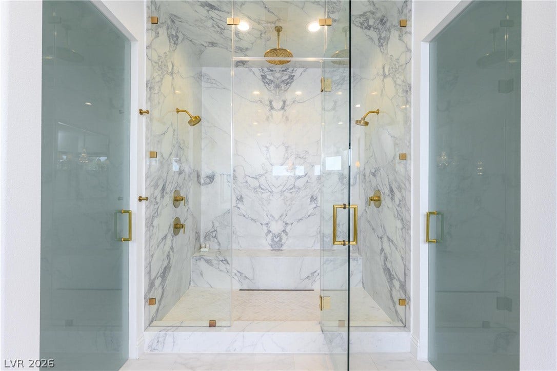 9817 Mountain Grove Court, Las Vegas, NV 89134 Bookmatched marble slabs and gold-toned hardware define this luxurious walk-in shower.