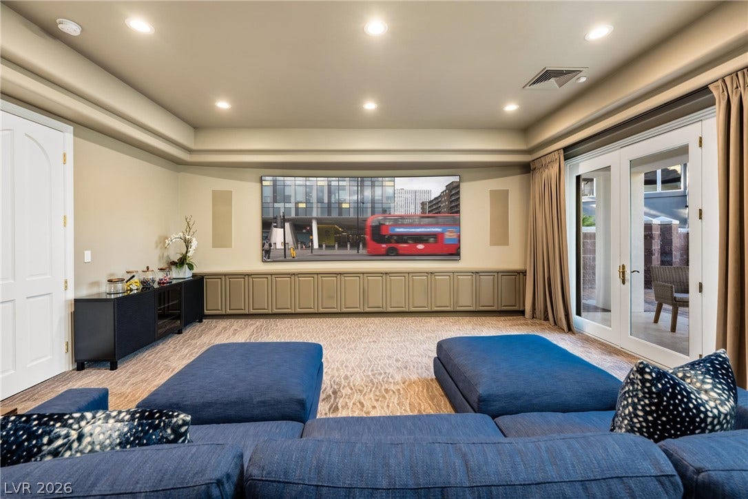 9817 Mountain Grove Court, Las Vegas, NV 89134 A spacious media room features patterned carpeting, elegant tray ceilings, and glass doors opening outside.