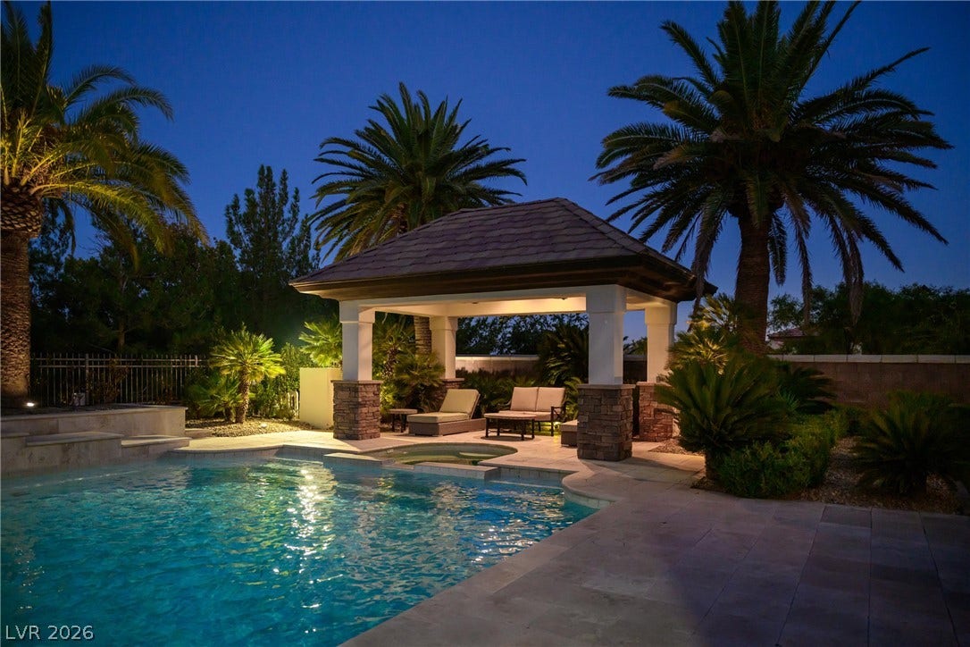 9817 Mountain Grove Court, Las Vegas, NV 89134 An inviting stone-pillared pavilion overlooks the sparkling pool, framed by tropical palm trees.