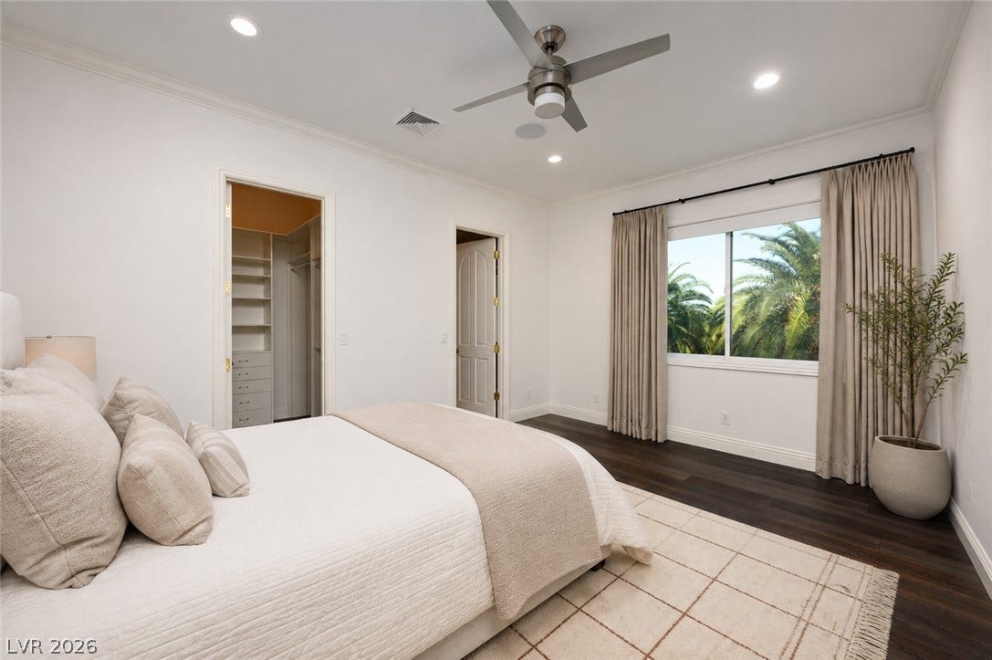 9817 Mountain Grove Court, Las Vegas, NV 89134 Rich dark wood flooring and a custom walk-in closet highlight this serene bedroom space.
