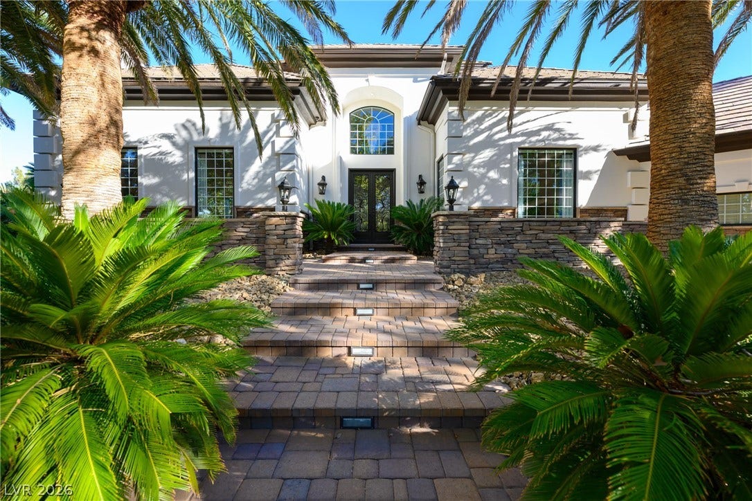9817 Mountain Grove Court, Las Vegas, NV 89134 Stately stone-accented architecture framing a grand double-door entrance with integrated step lighting.