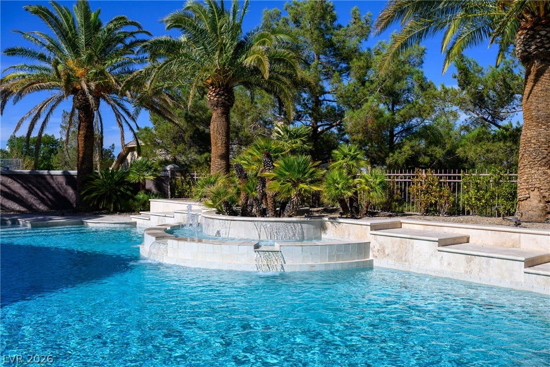 9817 Mountain Grove Court, Las Vegas, NV 89134 Lush palm trees and cascading stone waterfalls frame this sparkling backyard oasis.