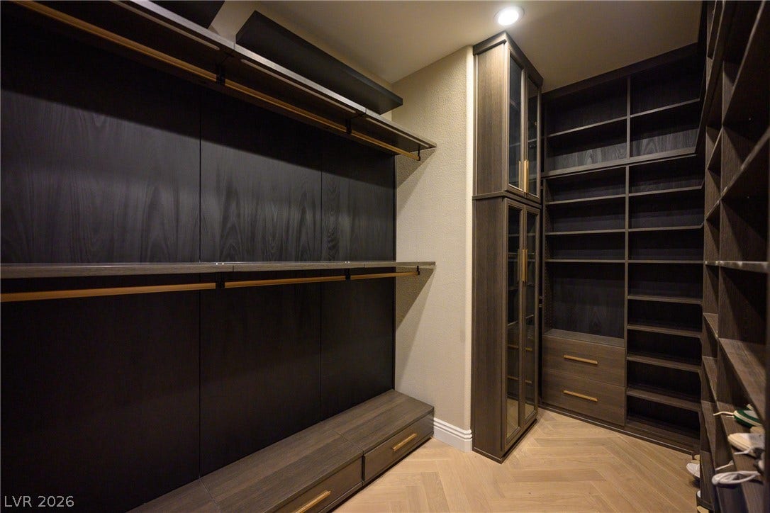 9817 Mountain Grove Court, Las Vegas, NV 89134 Rich wood shelving and herringbone patterned floors define this custom walk-in closet space.