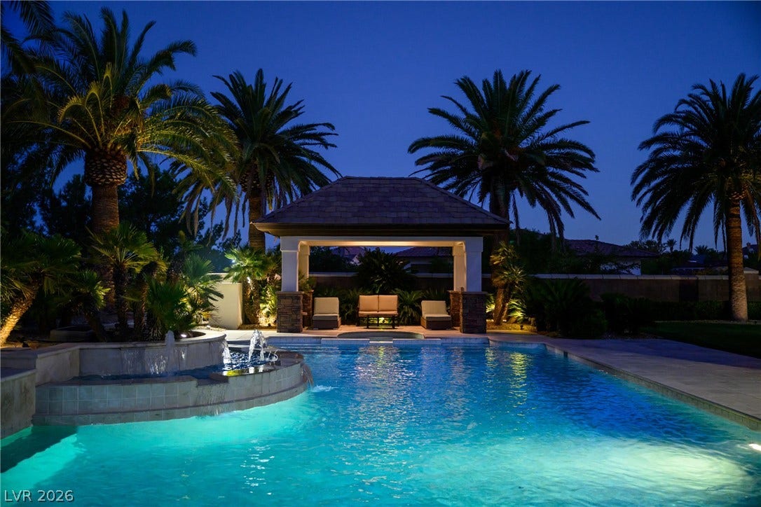 9817 Mountain Grove Court, Las Vegas, NV 89134 Palm trees frame a sparkling pool and a covered pavilion under the evening sky.