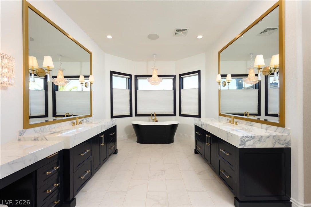 9817 Mountain Grove Court, Las Vegas, NV 89134 Marble counters and tile floors flank a freestanding tub under large gilded mirrors.