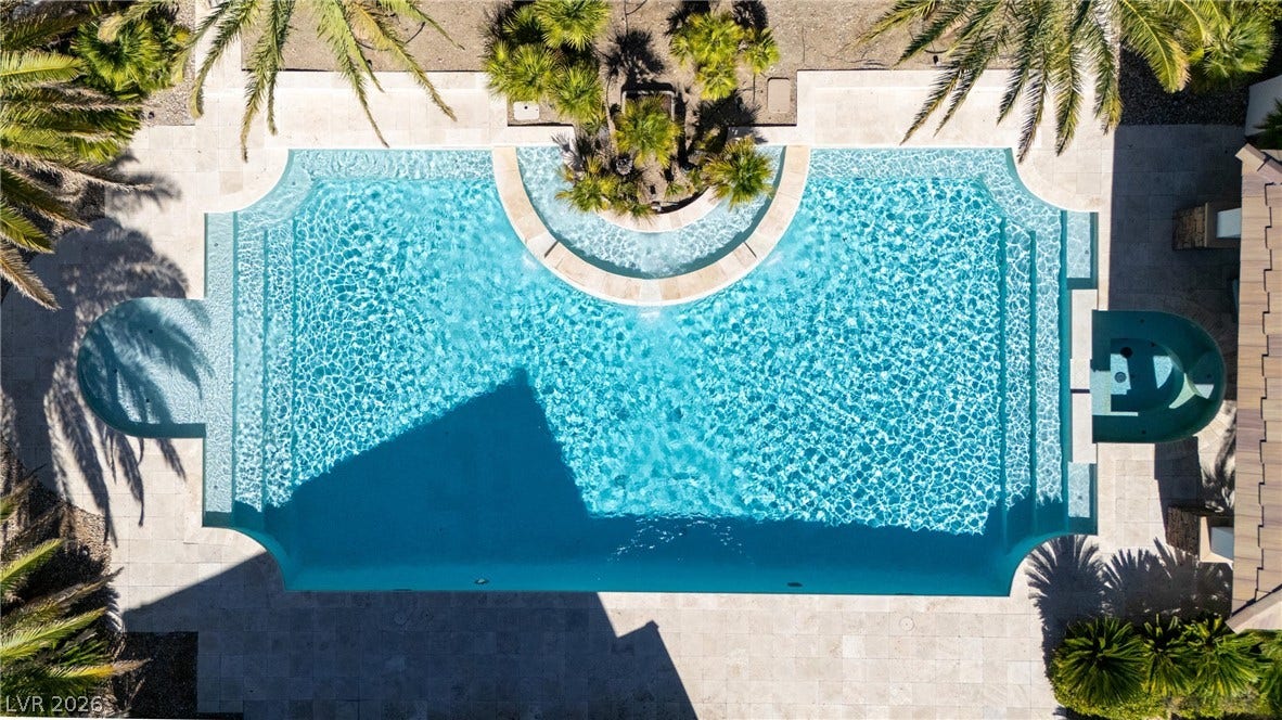 9817 Mountain Grove Court, Las Vegas, NV 89134 An elegant swimming pool is framed by classic stone paving and mature palm trees.