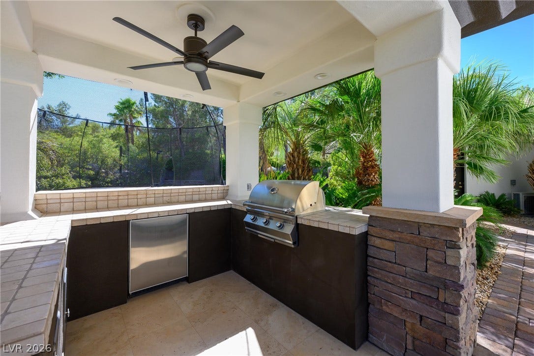 9817 Mountain Grove Court, Las Vegas, NV 89134 An outdoor kitchen features tiled countertops, stone accents, and a built-in stainless steel grill.