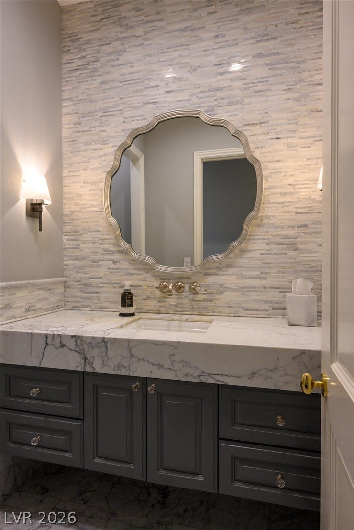 9817 Mountain Grove Court, Las Vegas, NV 89134 Elegant stone counters and custom wall tiling elevate this well-appointed washroom.