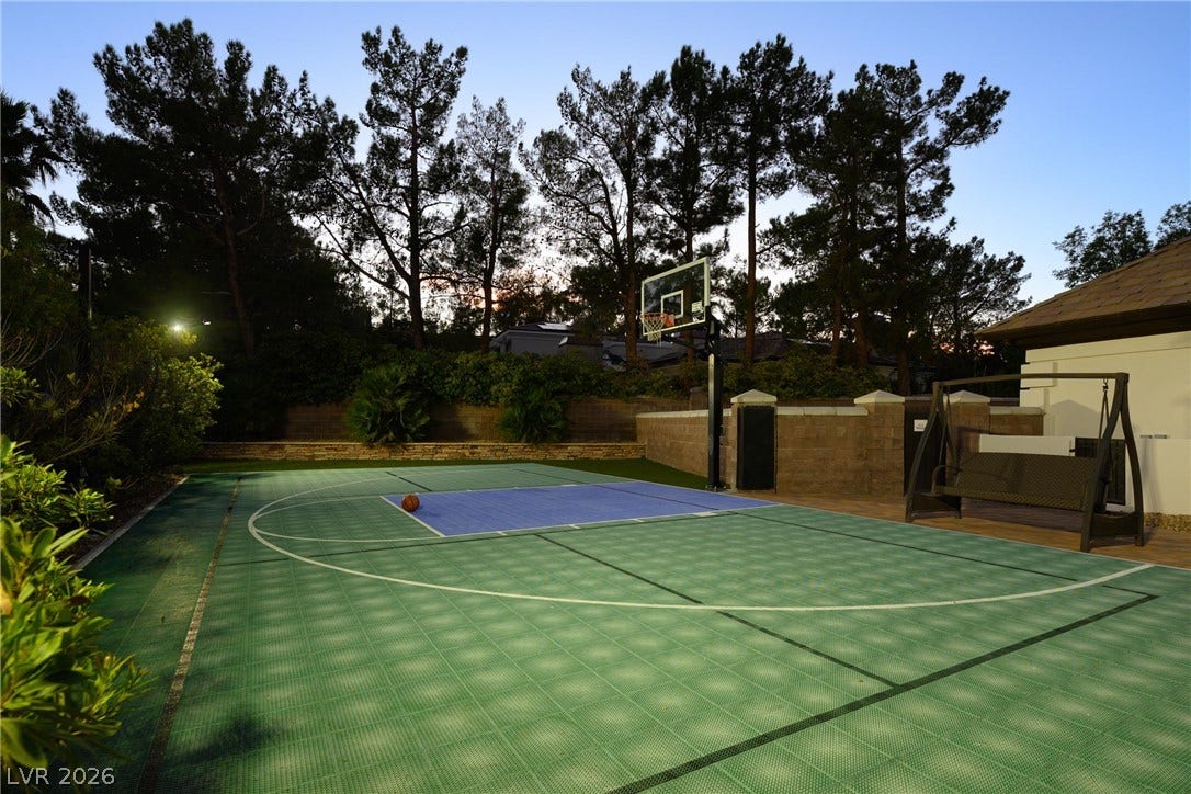9817 Mountain Grove Court, Las Vegas, NV 89134 A private outdoor basketball court is bordered by mature trees and stone retaining walls.