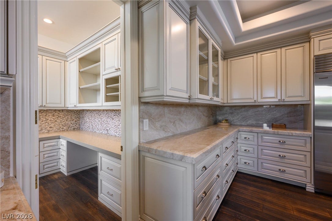 9817 Mountain Grove Court, Las Vegas, NV 89134 Rich hardwood floors anchor this custom butler pantry and kitchen workspace featuring stone countertops.
