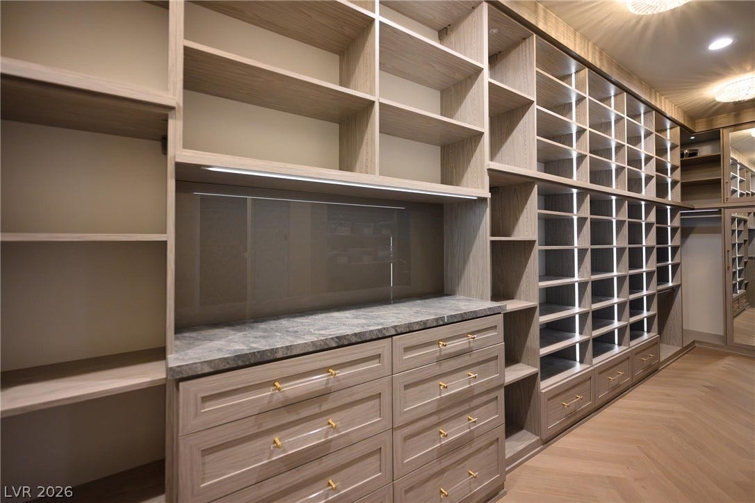 9817 Mountain Grove Court, Las Vegas, NV 89134 Custom wood shelving and built-in dressers line this spacious walk-in closet with herringbone flooring.