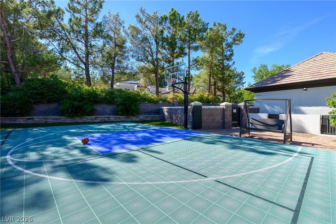 9817 Mountain Grove Court, Las Vegas, NV 89134 Tall pine trees frame a private backyard sports court equipped with a basketball hoop.