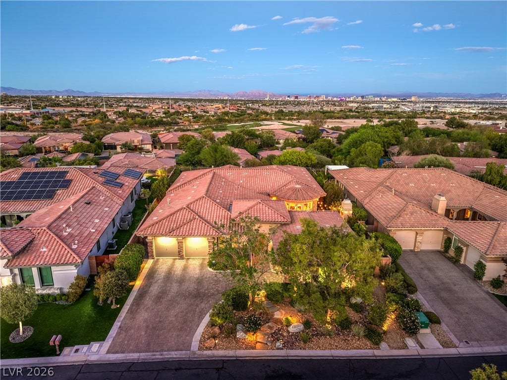 24 CROSS RIDGE Street, Las Vegas, NV 89135 Distant city skyline views frame this elegant desert home featuring a tiled roof and paved driveway.