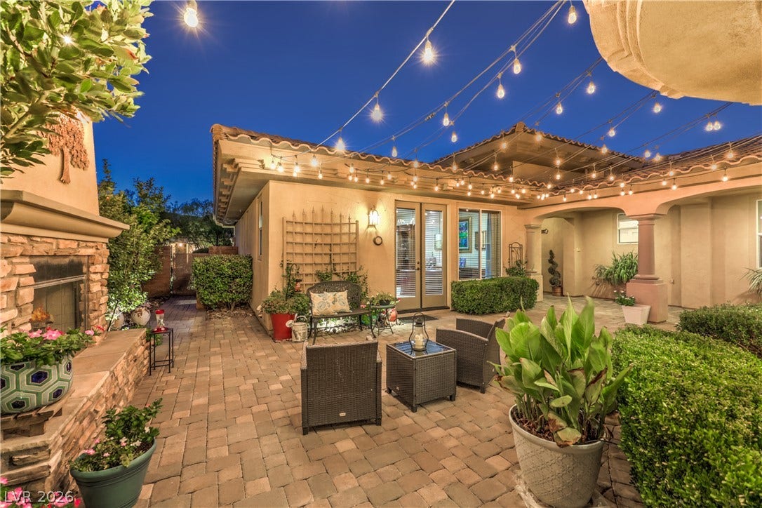 24 CROSS RIDGE Street, Las Vegas, NV 89135 An inviting stone-paved courtyard features a built-in outdoor fireplace and festive string lighting overhead.