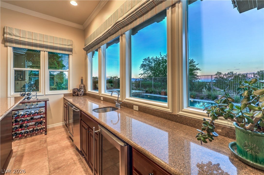 24 CROSS RIDGE Street, Las Vegas, NV 89135 Polished stone countertops line this walk-in bar under a wall of windows overlooking the pool.