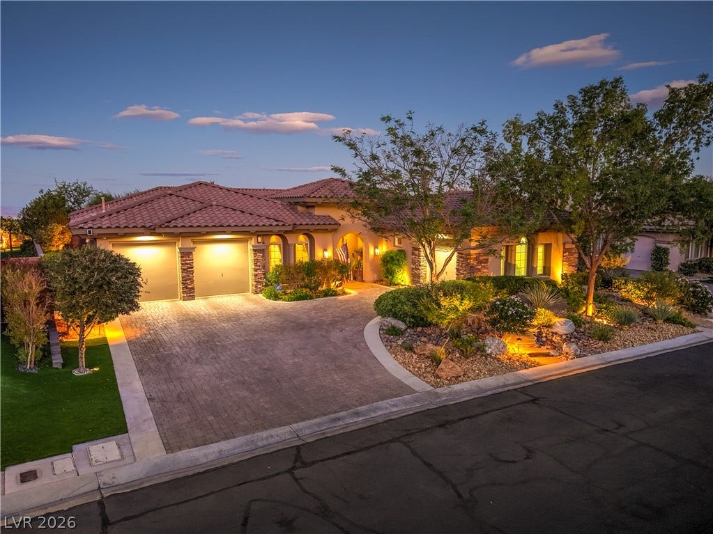 24 CROSS RIDGE Street, Las Vegas, NV 89135 A spacious driveway and meticulously landscaped front yard frame this elegant single-story home at twilight.