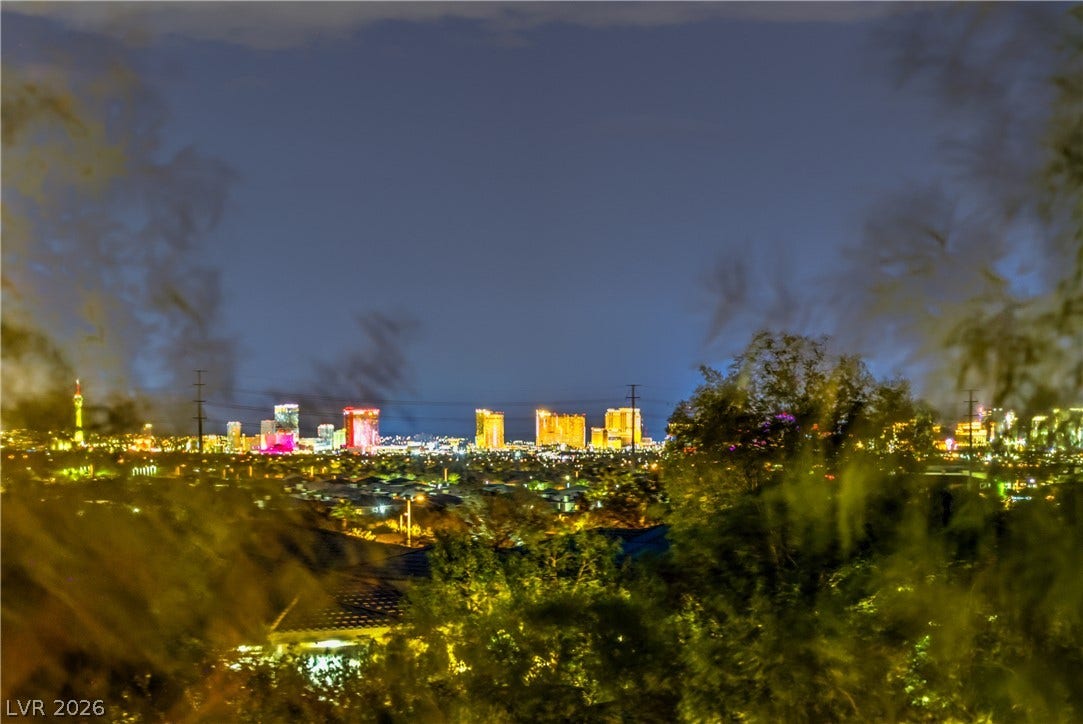 24 CROSS RIDGE Street, Las Vegas, NV 89135 Glittering city skyline views create a dramatic backdrop beyond the lush treetops.