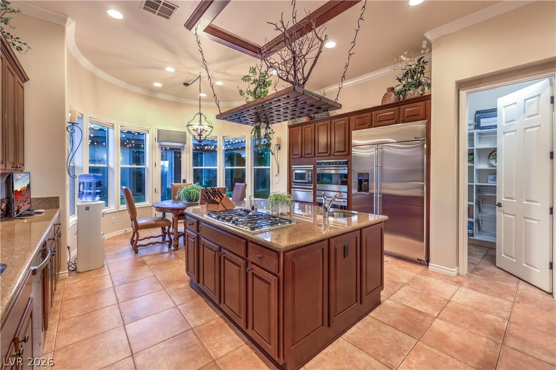 24 CROSS RIDGE Street, Las Vegas, NV 89135 Rich wood cabinetry and a central island highlight this gourmet kitchen with tile flooring.