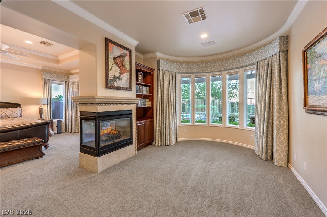 24 CROSS RIDGE Street, Las Vegas, NV 89135 An elegant sitting area features a curved wall of windows and a see-through stone fireplace.