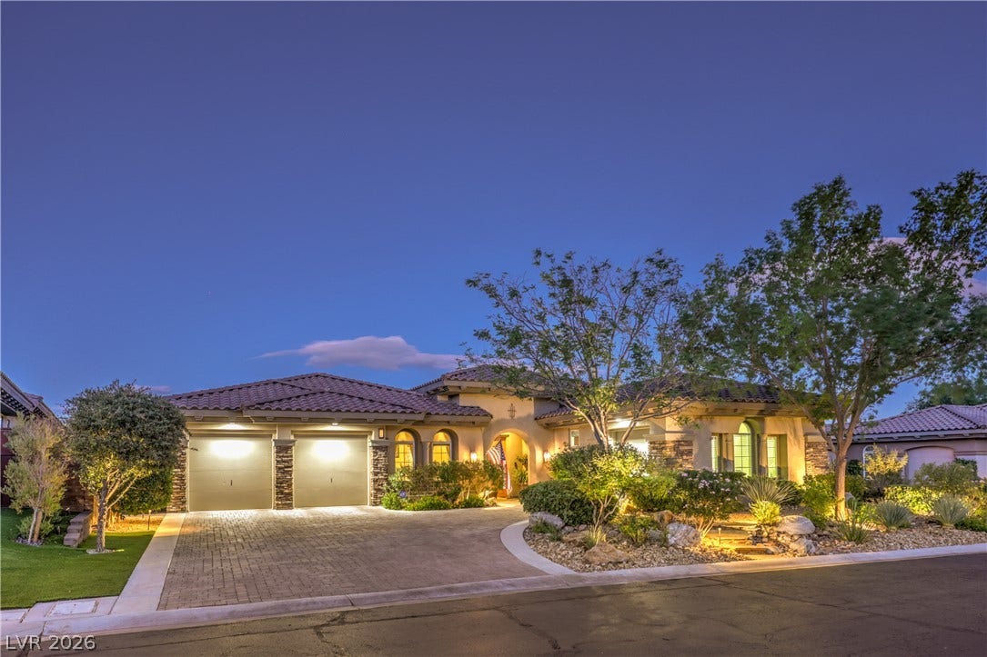24 CROSS RIDGE Street, Las Vegas, NV 89135 Warm exterior lighting highlights this elegant desert home featuring a tiled roof and stone accents.