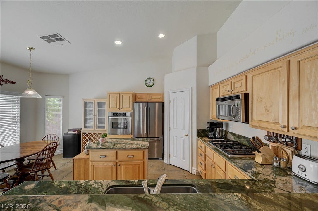 2201 Double Tree Avenue, Henderson, NV 89052 Granite countertops and honey-toned wood cabinetry define this kitchen featuring a central preparation island.