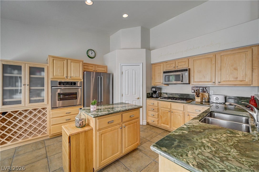 2201 Double Tree Avenue, Henderson, NV 89052 Rich stone countertops and light wood cabinetry anchor this functional cooking space.