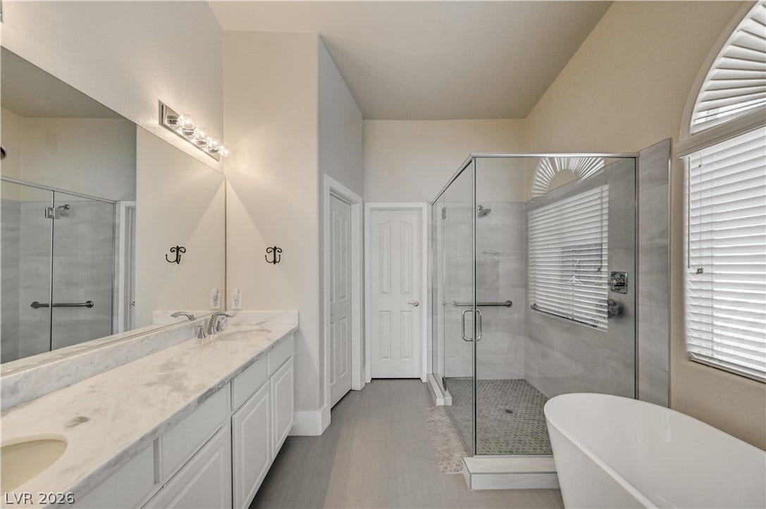 2201 Double Tree Avenue, Henderson, NV 89052 High ceilings and stone counters elevate this modern bathroom featuring a standalone soaking tub.