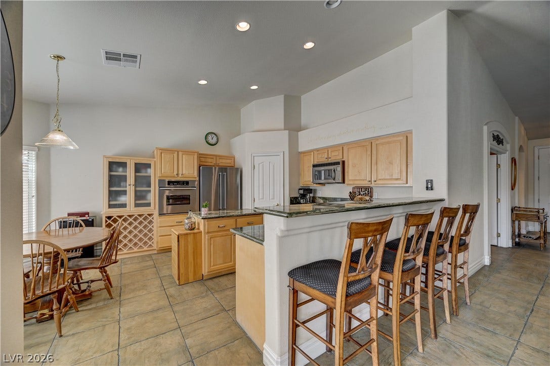 2201 Double Tree Avenue, Henderson, NV 89052 Tiled floors and wood cabinetry anchor this spacious kitchen complete with a breakfast bar.