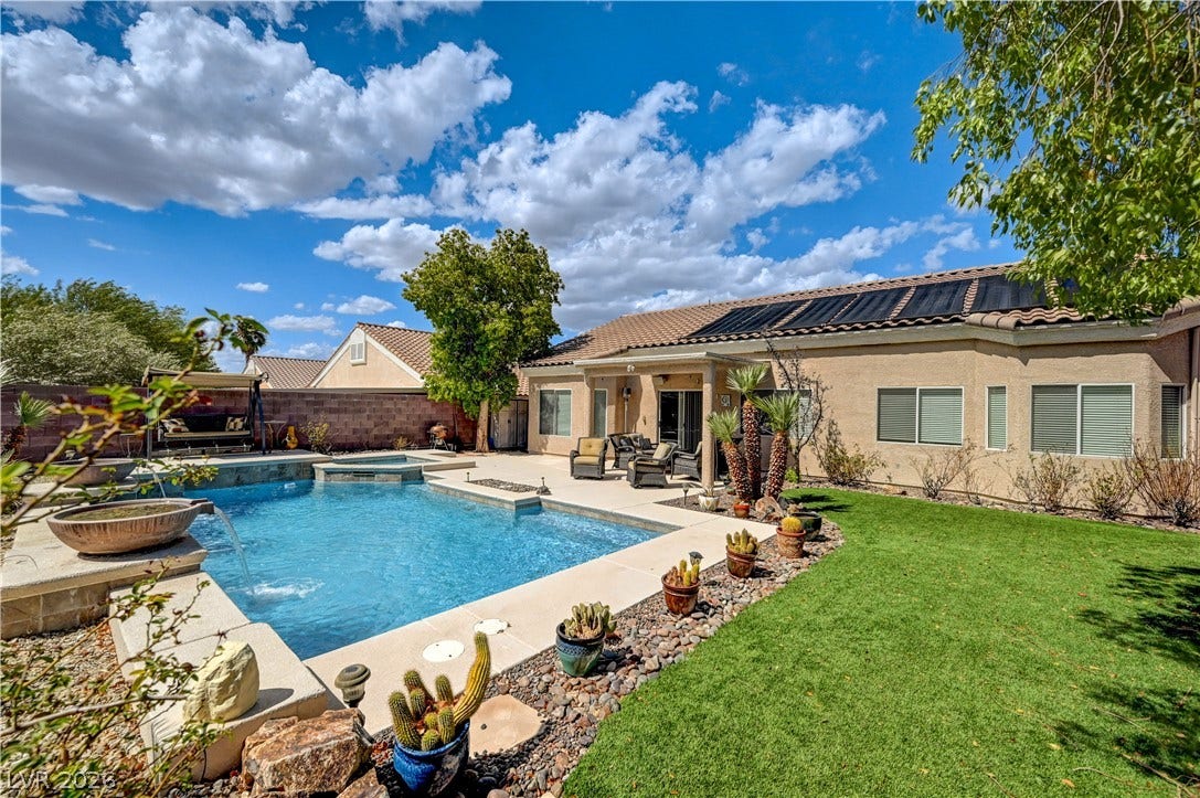 2201 Double Tree Avenue, Henderson, NV 89052 An inviting backyard oasis features a sparkling swimming pool alongside a lush green lawn.
