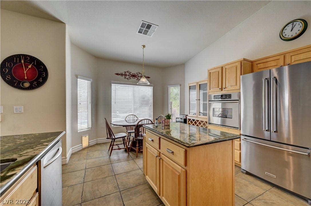 2201 Double Tree Avenue, Henderson, NV 89052 Gleaming stone countertops and a central island highlight this tiled kitchen and adjoining dining nook.