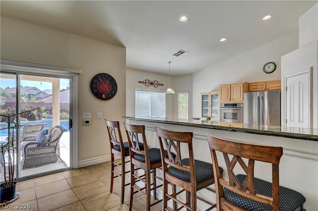 2201 Double Tree Avenue, Henderson, NV 89052 Granite counters highlight a raised breakfast bar overlooking a bright kitchen with sliding door access.